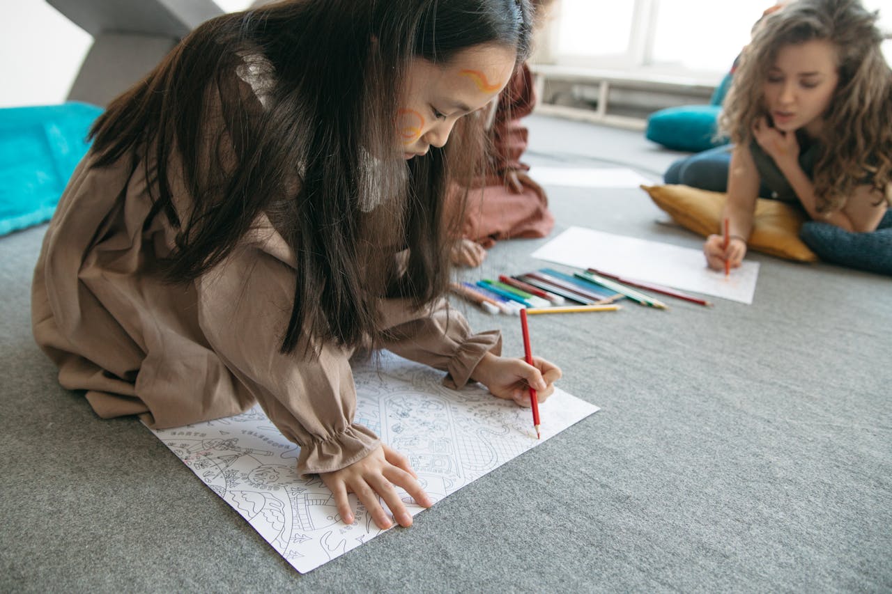 gallery-06 Child drawing with colored pencils indoors, focusing on creativity and art.