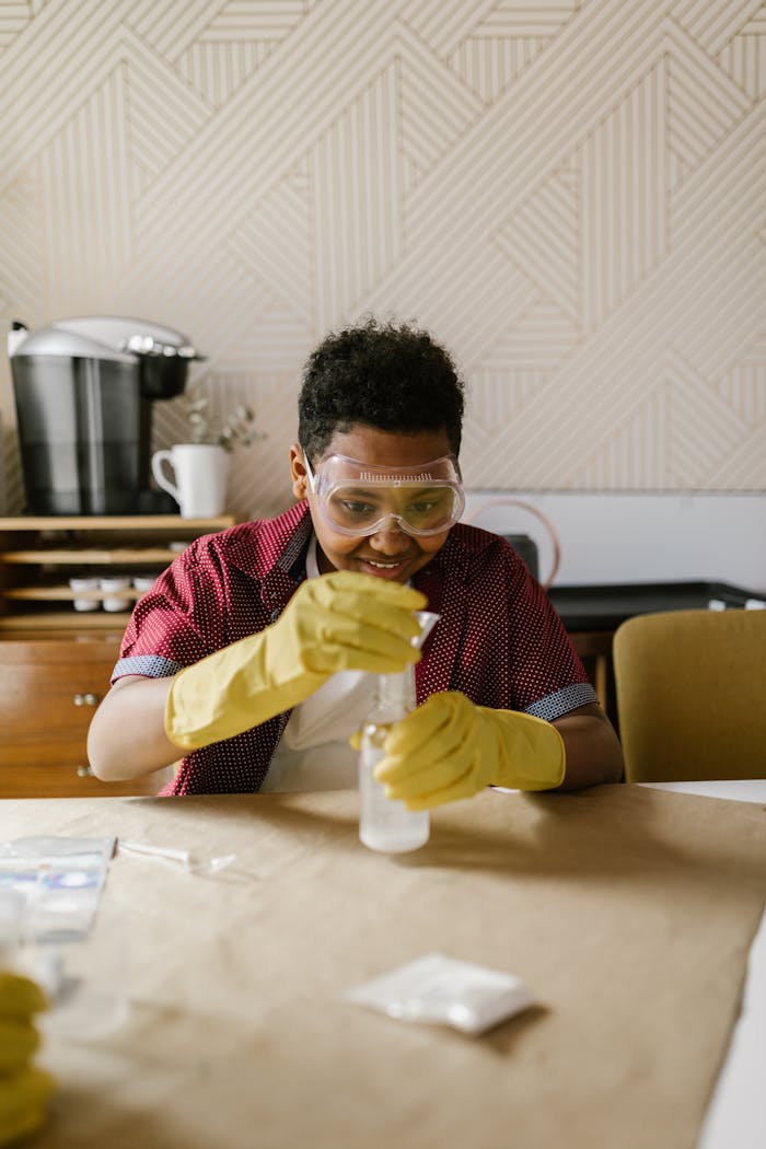 gallery-04 A child conducting a science experiment with concentration, wearing protective gear indoors.