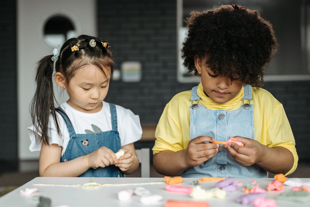 gallery-01 Two young children participate in an art workshop, focusing on sculpting activities indoors.